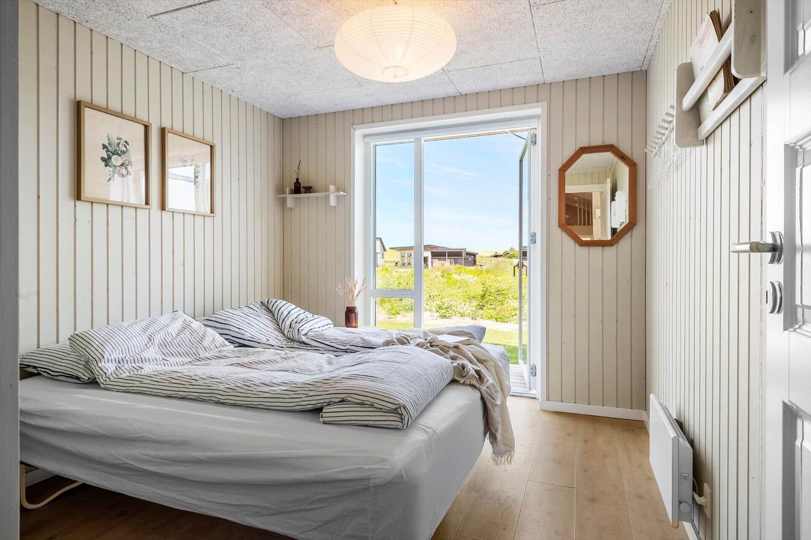 Schlafzimmer mit Bett, Fenster und Wanddekoration.