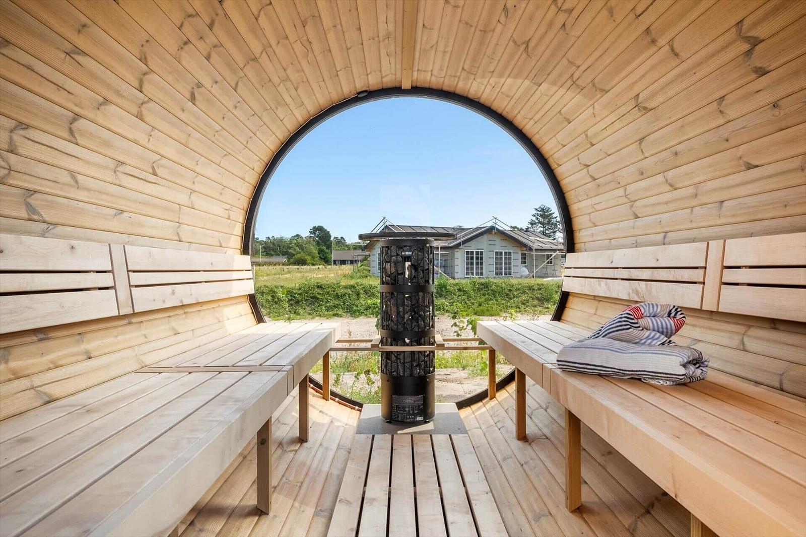 Sauna mit Holzbank und runden Fensterblick auf Haus und Grünflächen.