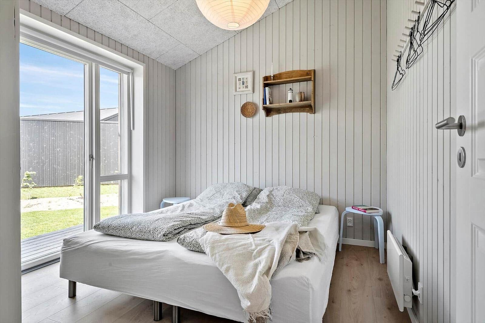 Bedroom with bed, window, and wood paneling.