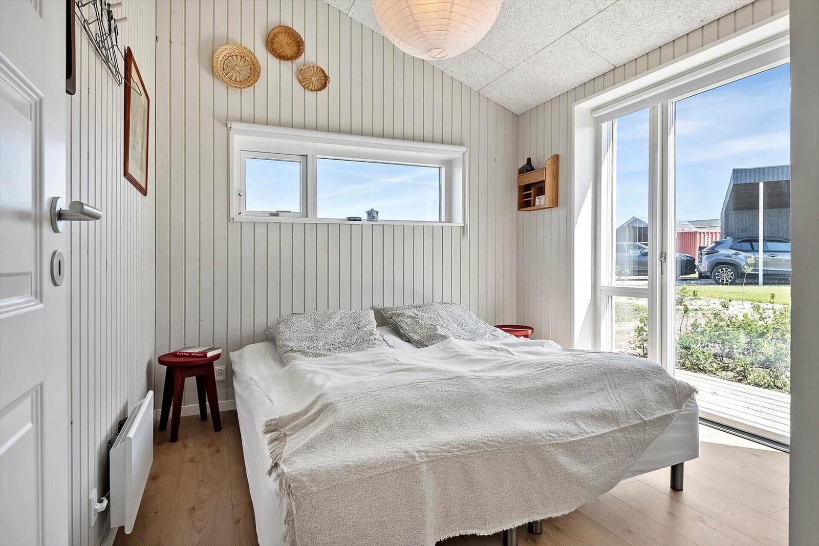 Bedroom with bed, window, and glass door to outdoor terrace.