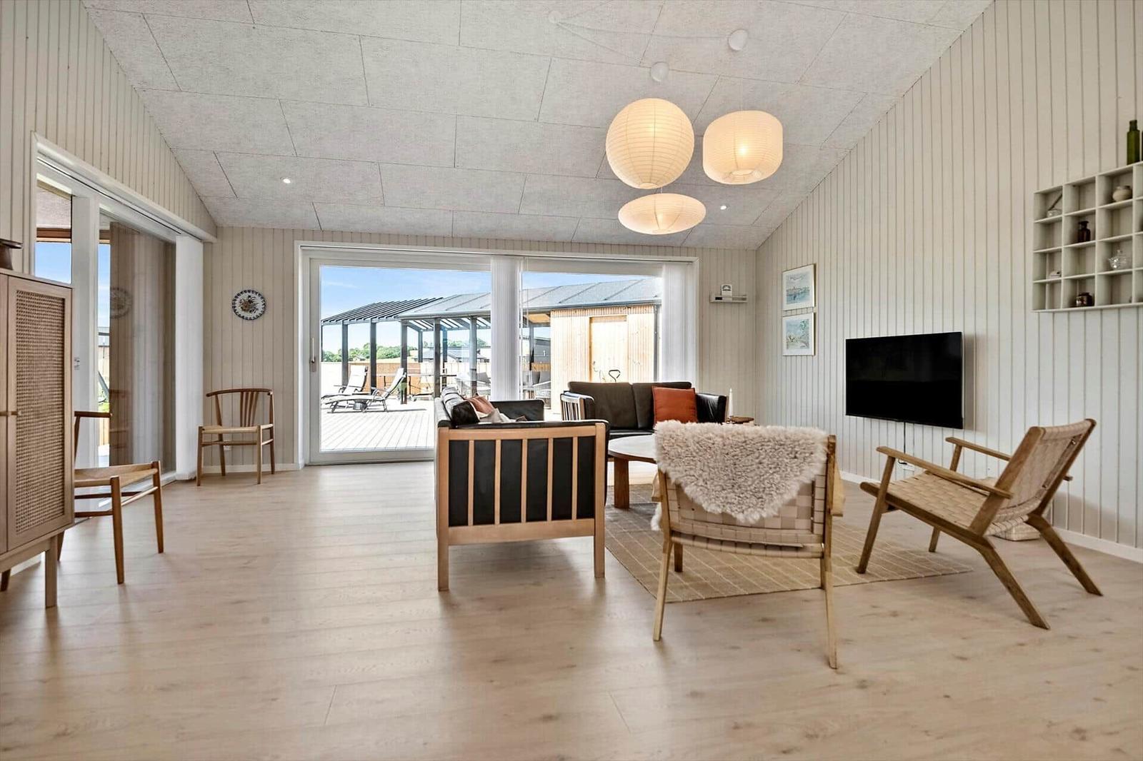 Living room with wooden floor, seating, and TV. Access to terrace.