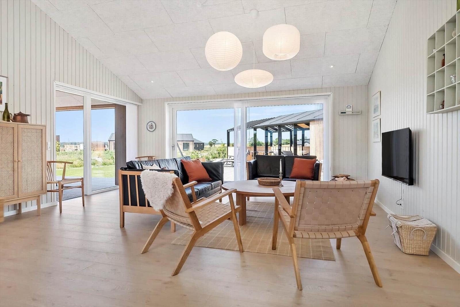 Living room with sofa, chairs, and TV. Doorways to terrace and garden.