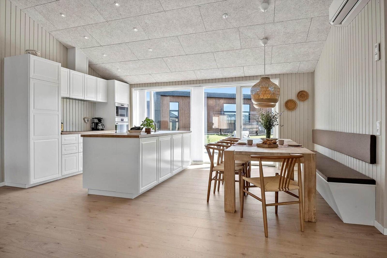 Kitchen with dining area, wooden floor, and windows to the garden.