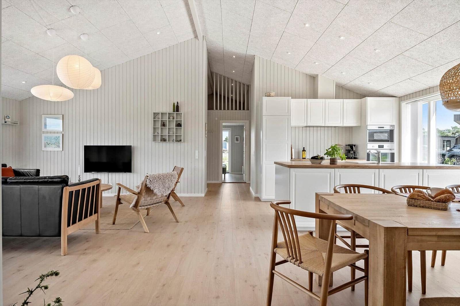 Living and dining area with wooden floor, white walls, and kitchen island.