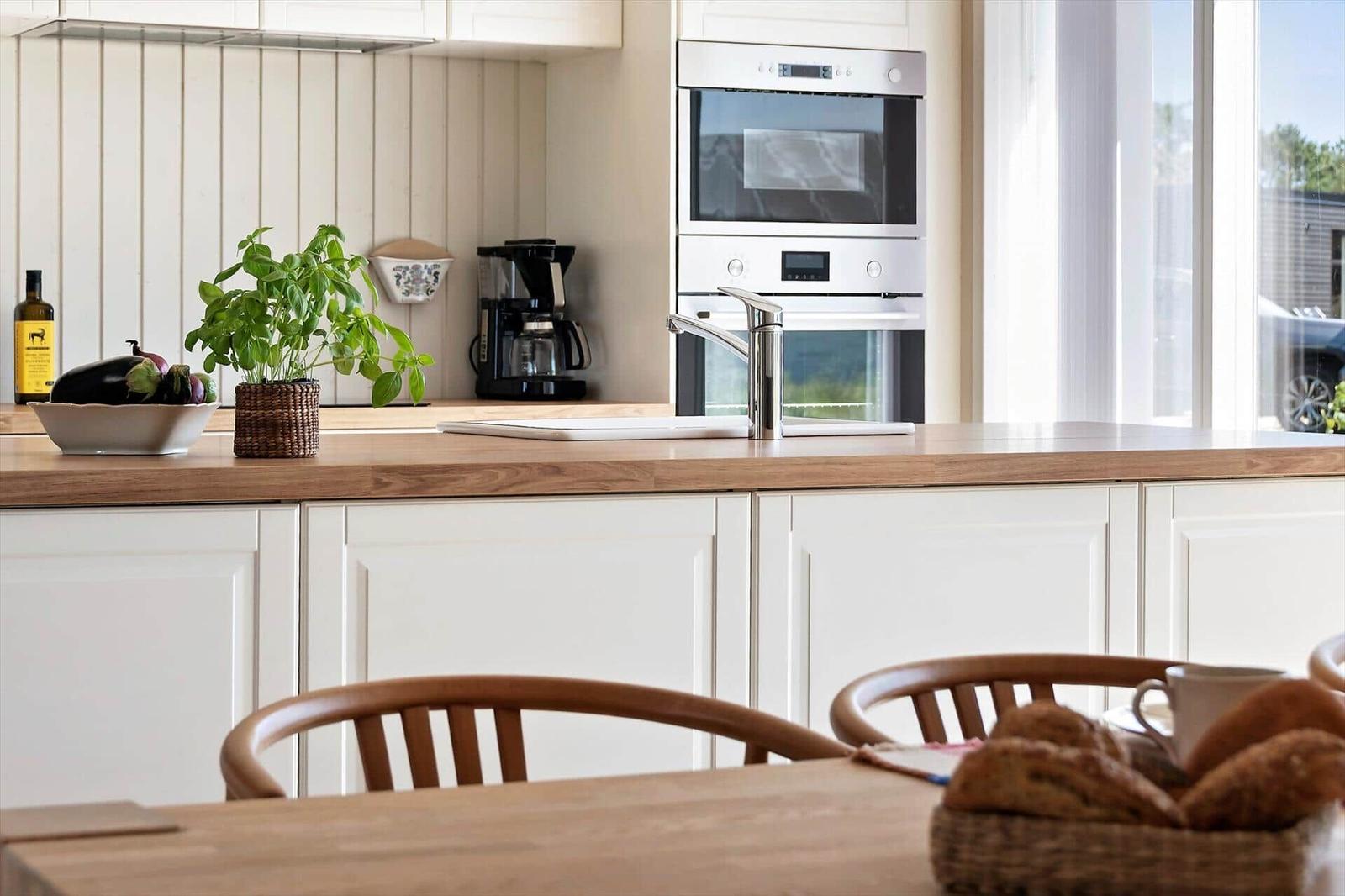 Kitchen with wooden countertop, white cabinets, and built-in oven. A basket with bread sits on the table.