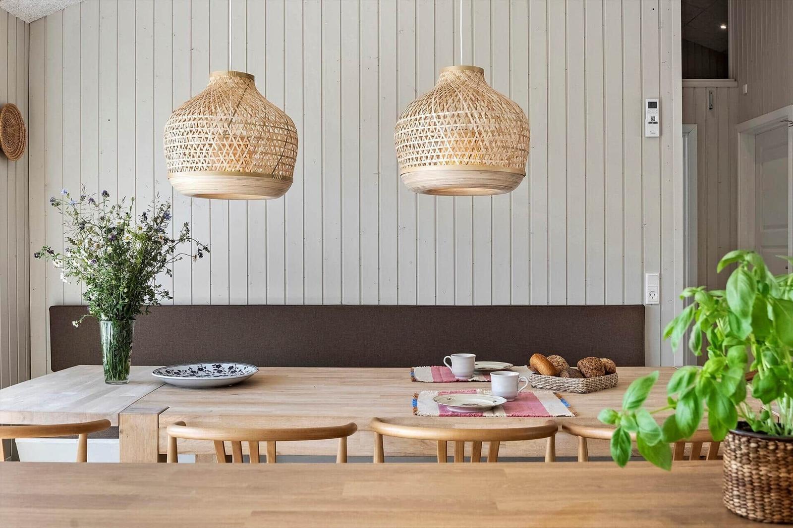 Dining room with wooden table, bamboo lamps, and plants.