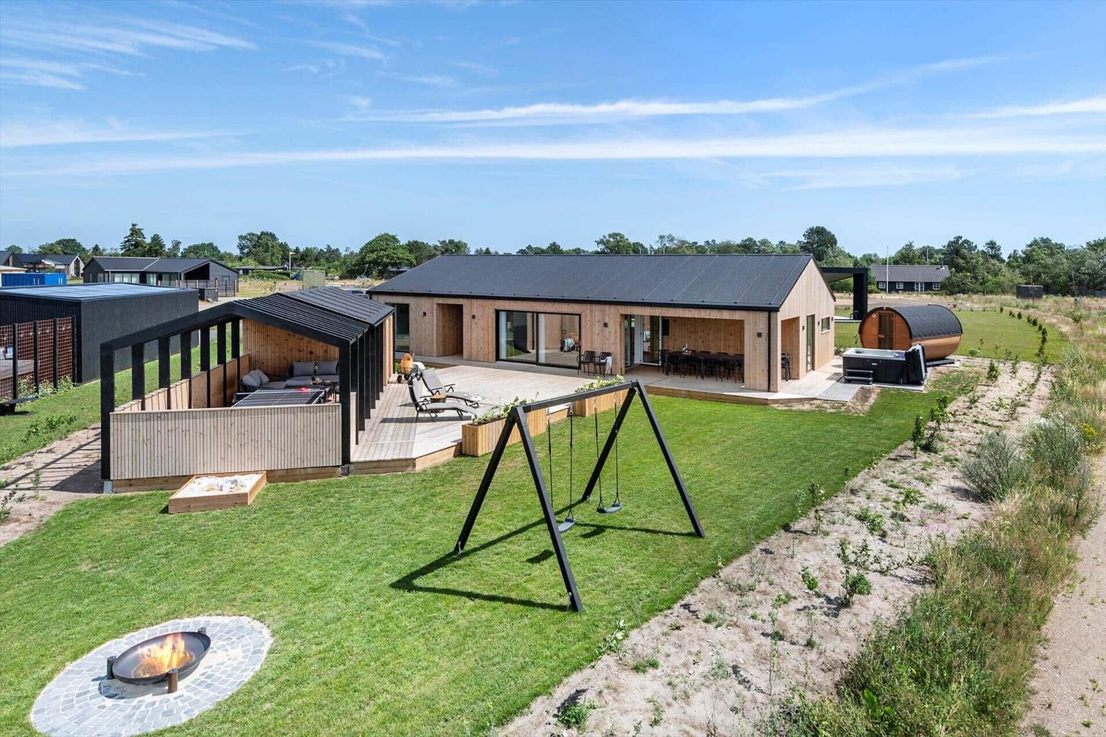 Modern wooden cabin with terrace, swing, fire pit, and sauna in the garden.