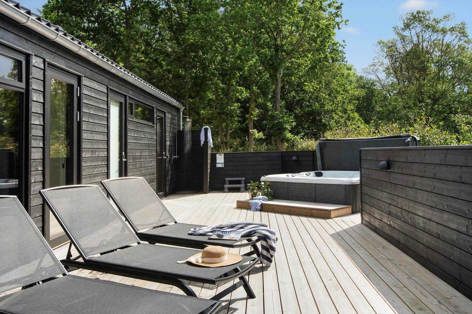 Terrasse mit Liegestühlen, Whirlpool und Duschmöglichkeit im Freien.