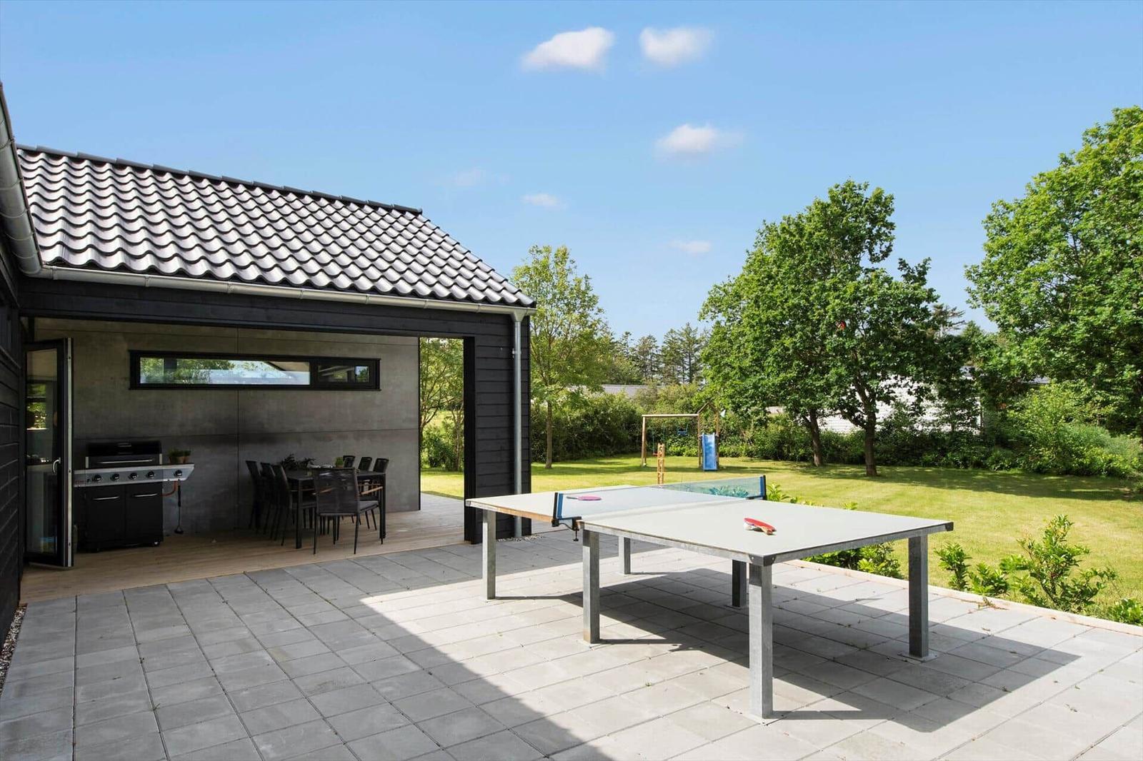 Außenbereich mit Tischtennisplatte, Grill und Sitzgruppe im Garten.
