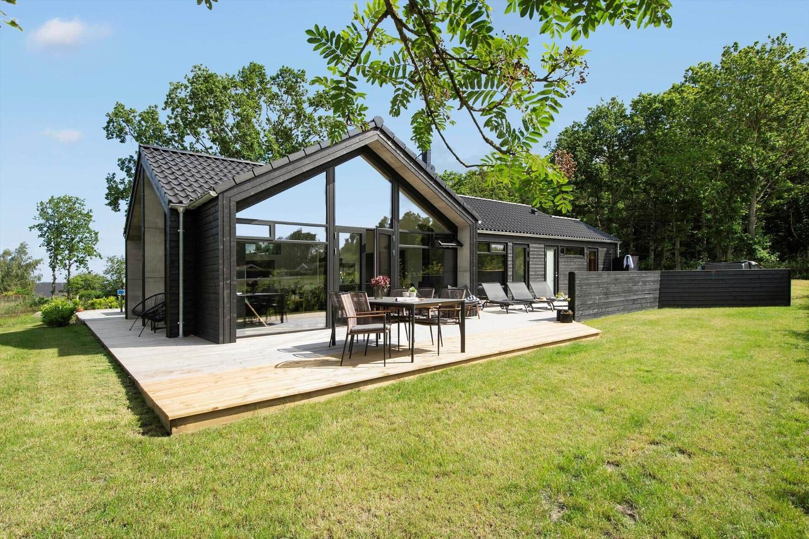 Moderne Villa mit großem Holzdeck, Garten und Terrasse mit Sitzgelegenheiten.