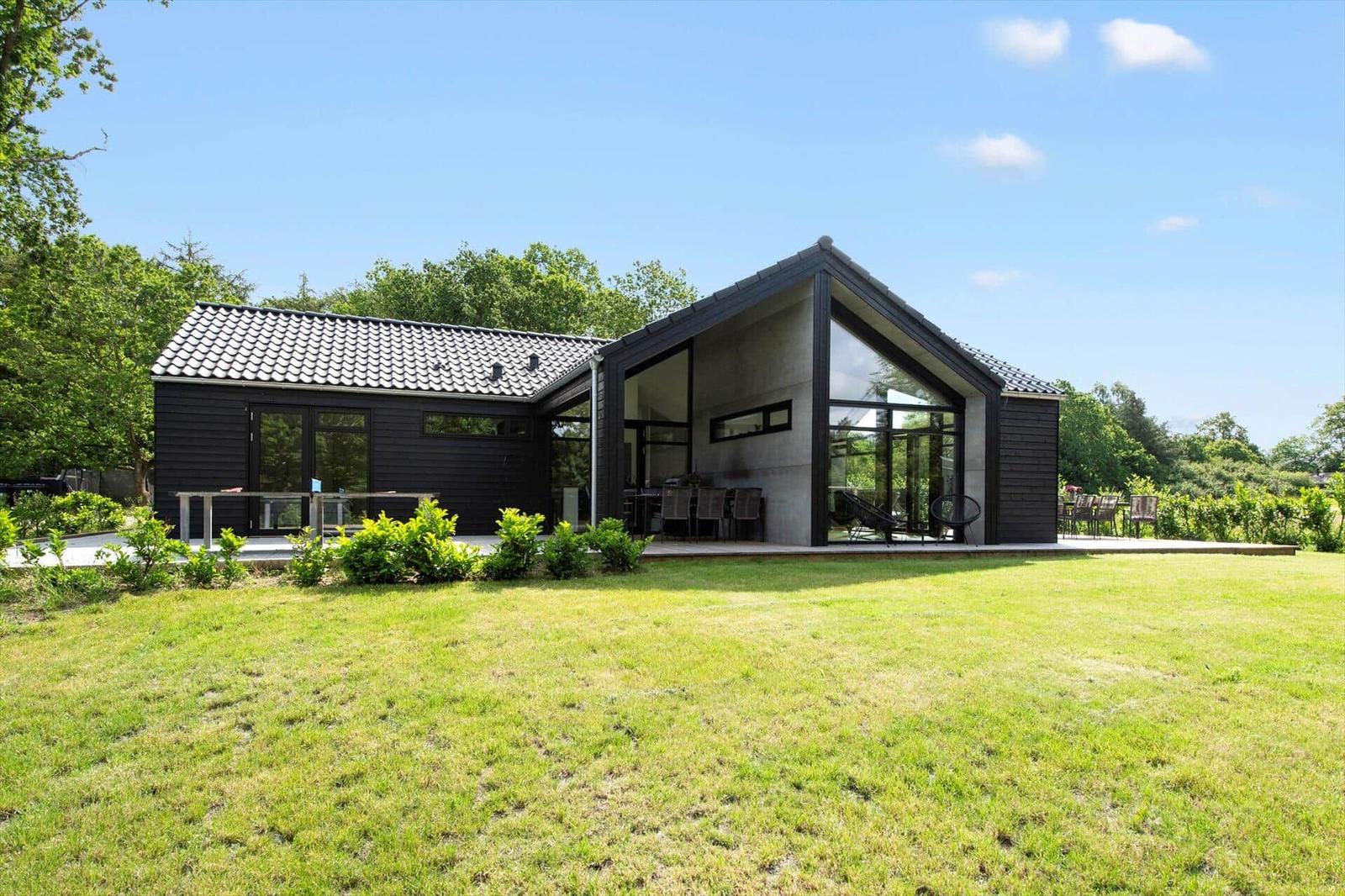 Moderne Villa mit großem Garten und Glasfront. Außenterrasse mit Sitzgelegenheiten.