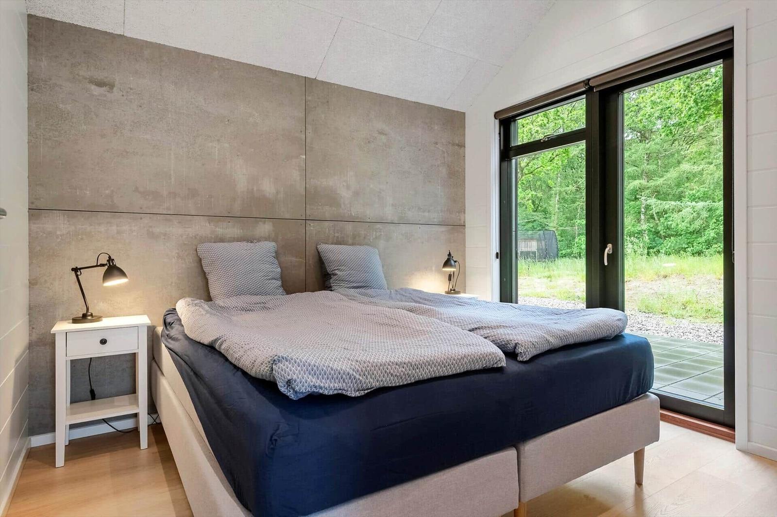 Schlafzimmer mit Bett, Nachttisch und Fenster zum Garten.