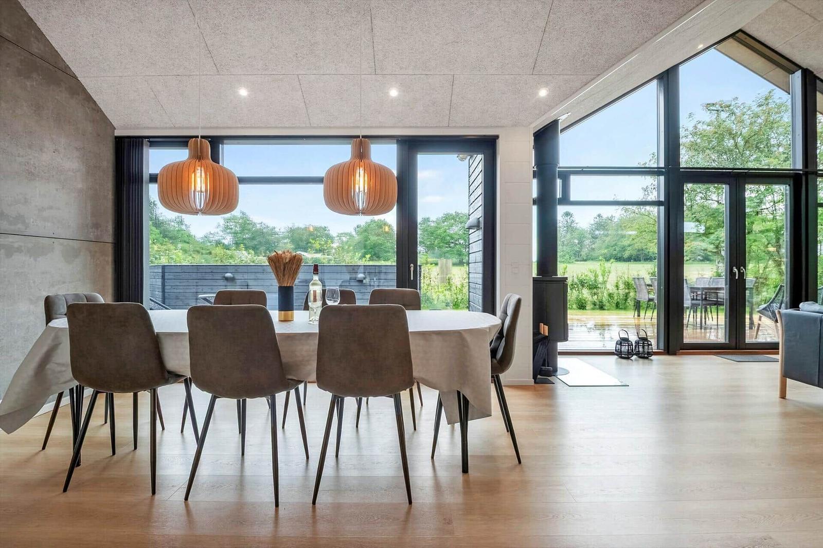 Esszimmer mit runden Tisch, Stühlen und großen Fenstern zur Terrasse.