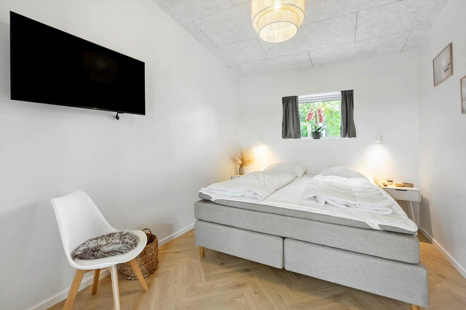 Schlafzimmer mit Bett, Fernseher und Fenster mit Blick nach draußen.