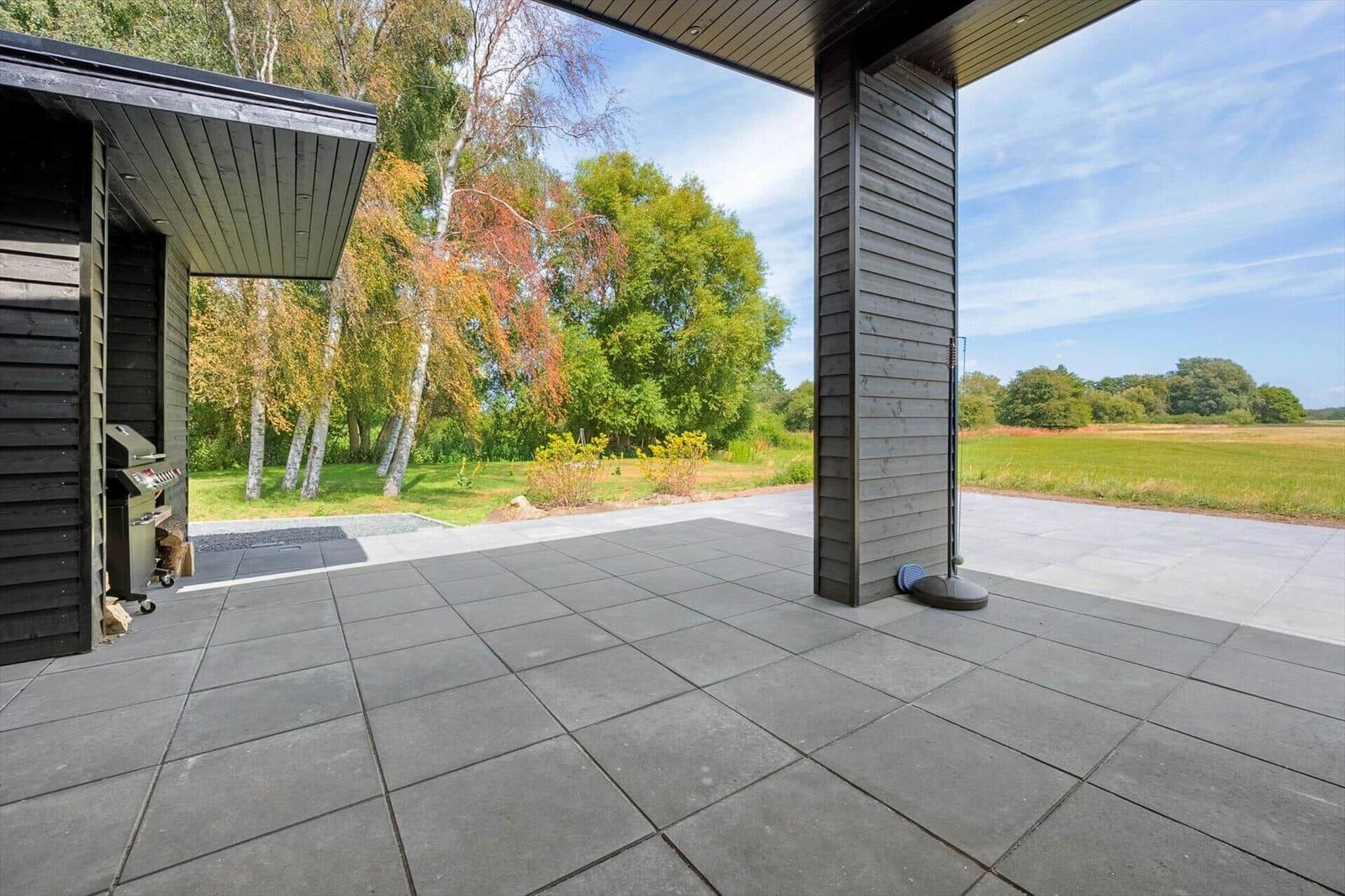Geräumige Terrasse mit Grill und Blick auf Wald und Feld.