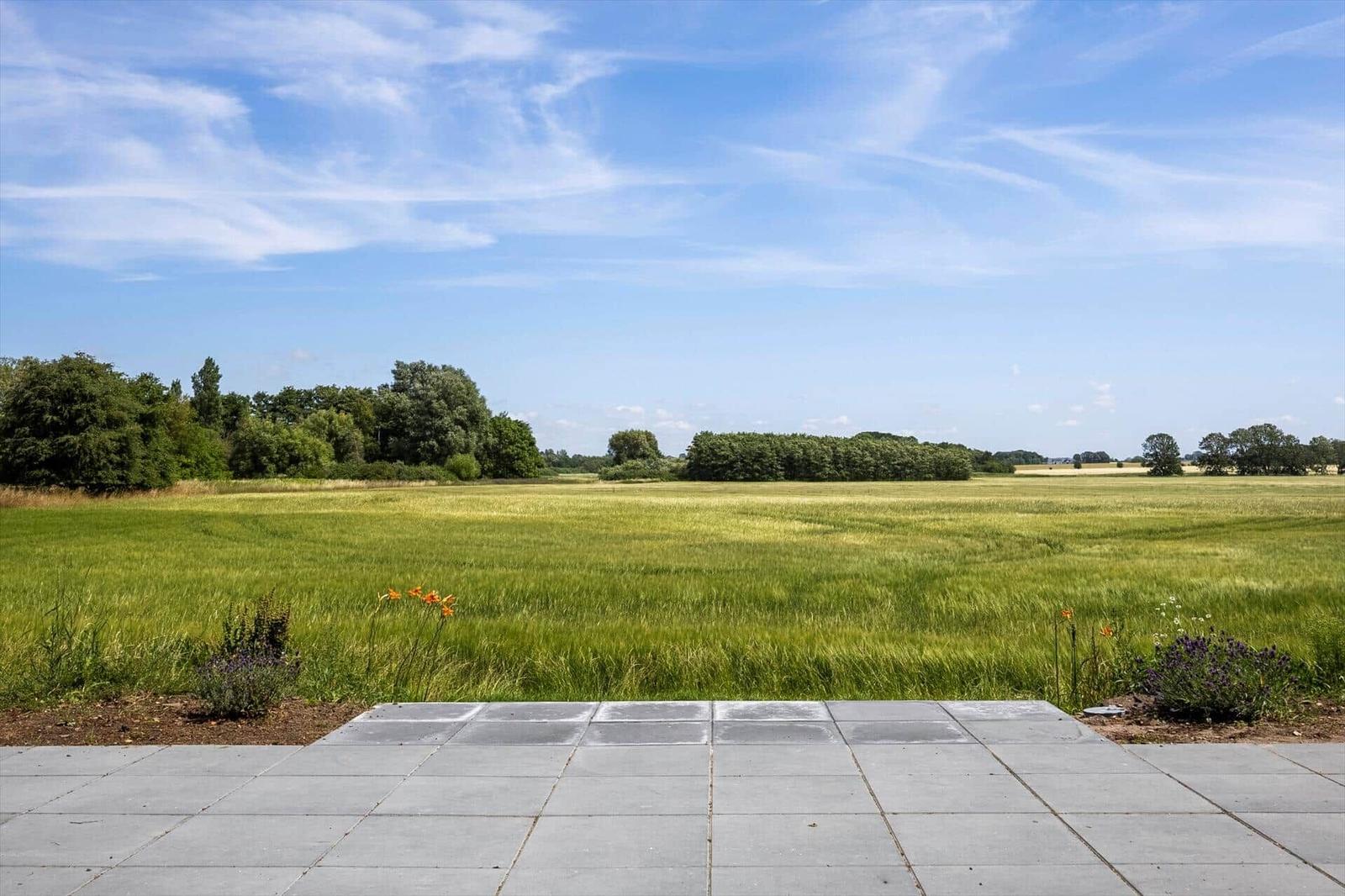 Terrasse mit Blick auf grünes Feld und blauen Himmel.