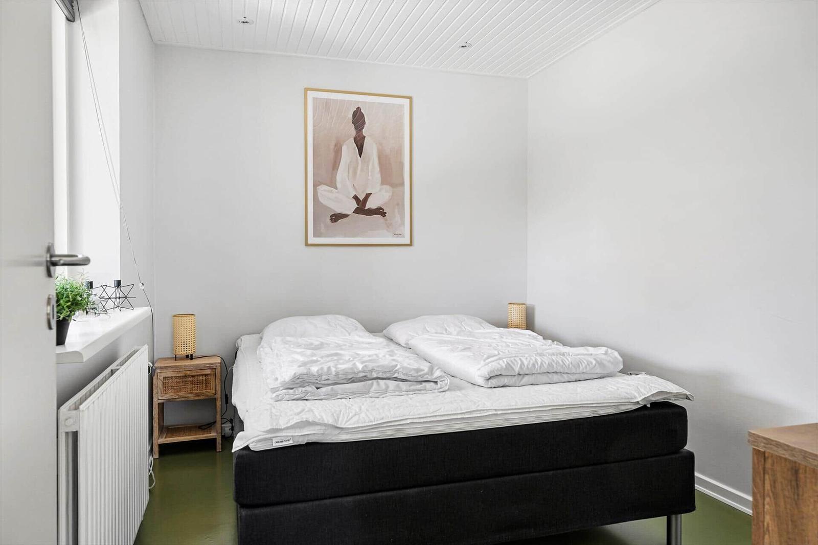 Bedroom with bed, nightstand, and wall art.