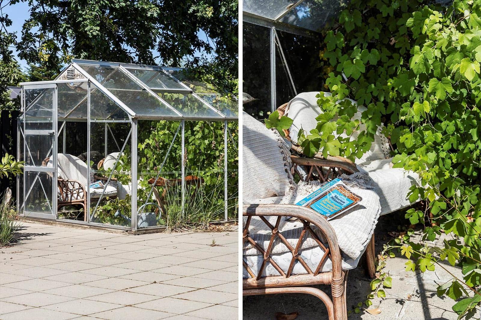 Glass greenhouse with seating area in the garden. Plants and sun provide a calm atmosphere.