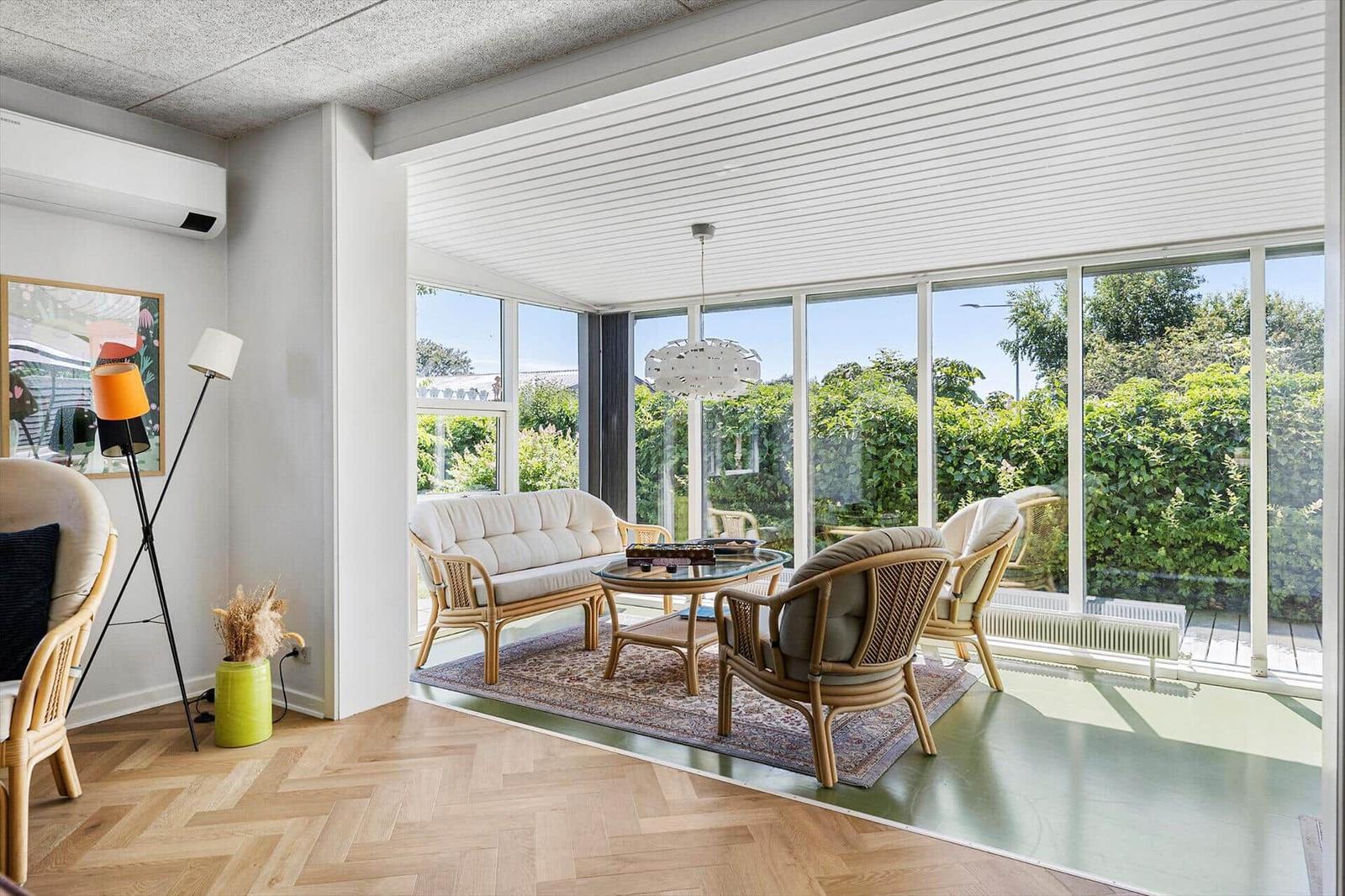 A living area with seating, glass wall, and view of green trees.