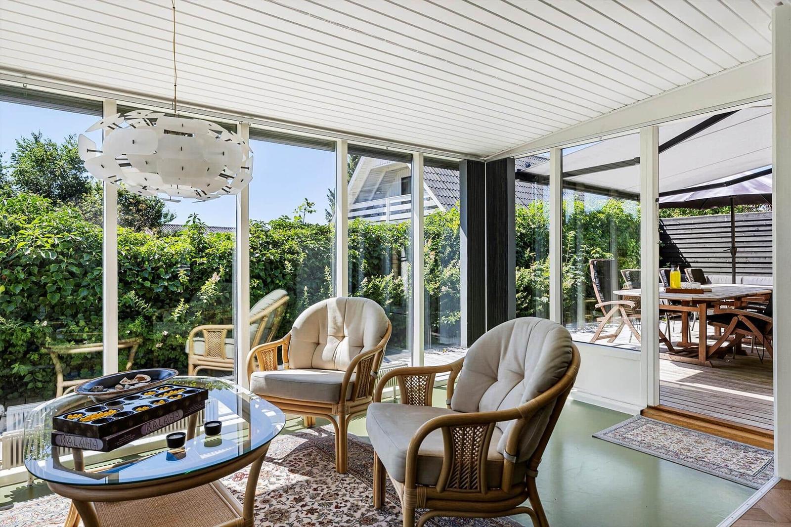 Glass roof with seating and garden view. Table with toys and rug.