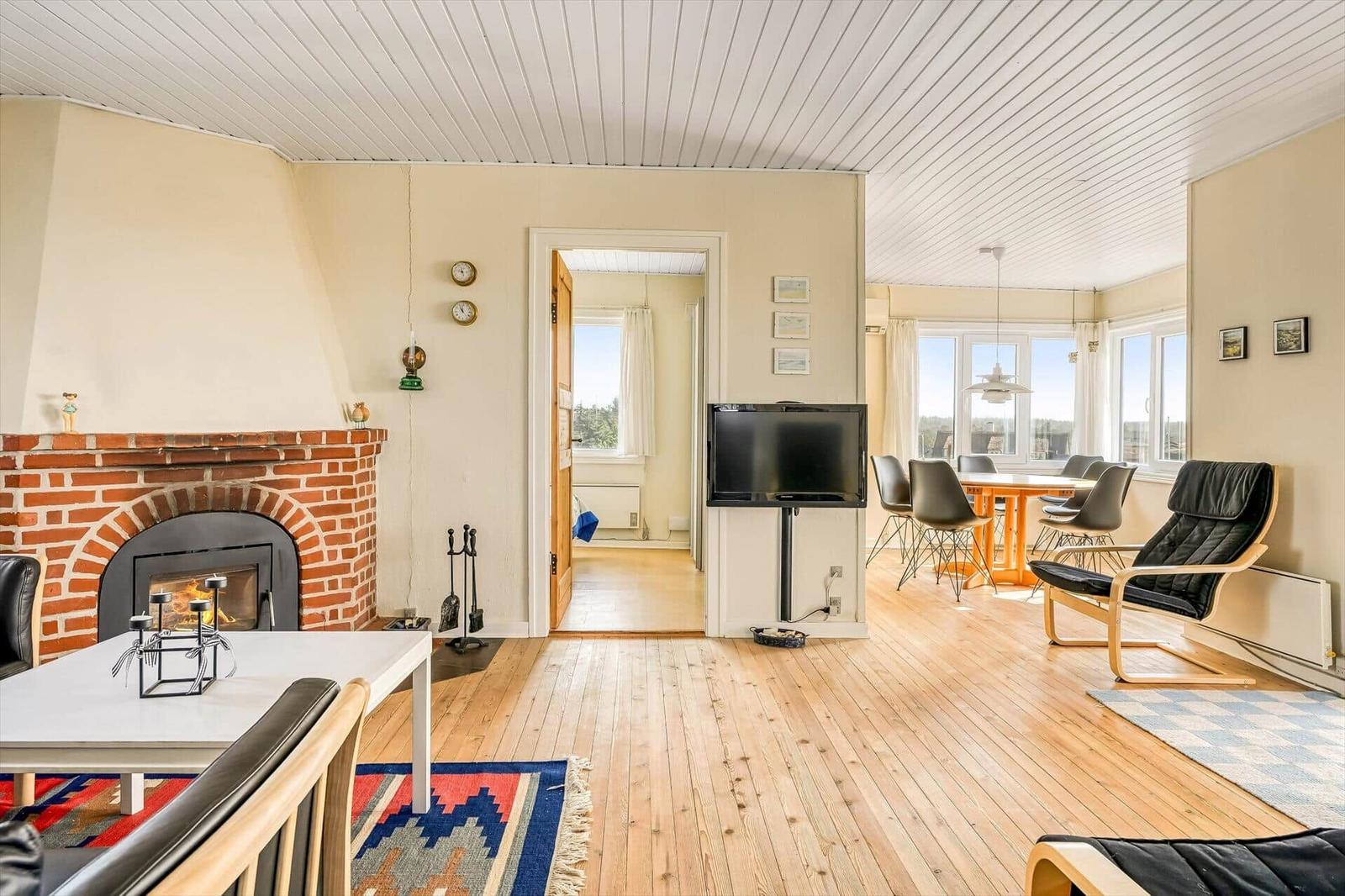 Wohnzimmer mit Kamin, Fernseher und Essbereich mit Tisch und Stühlen.