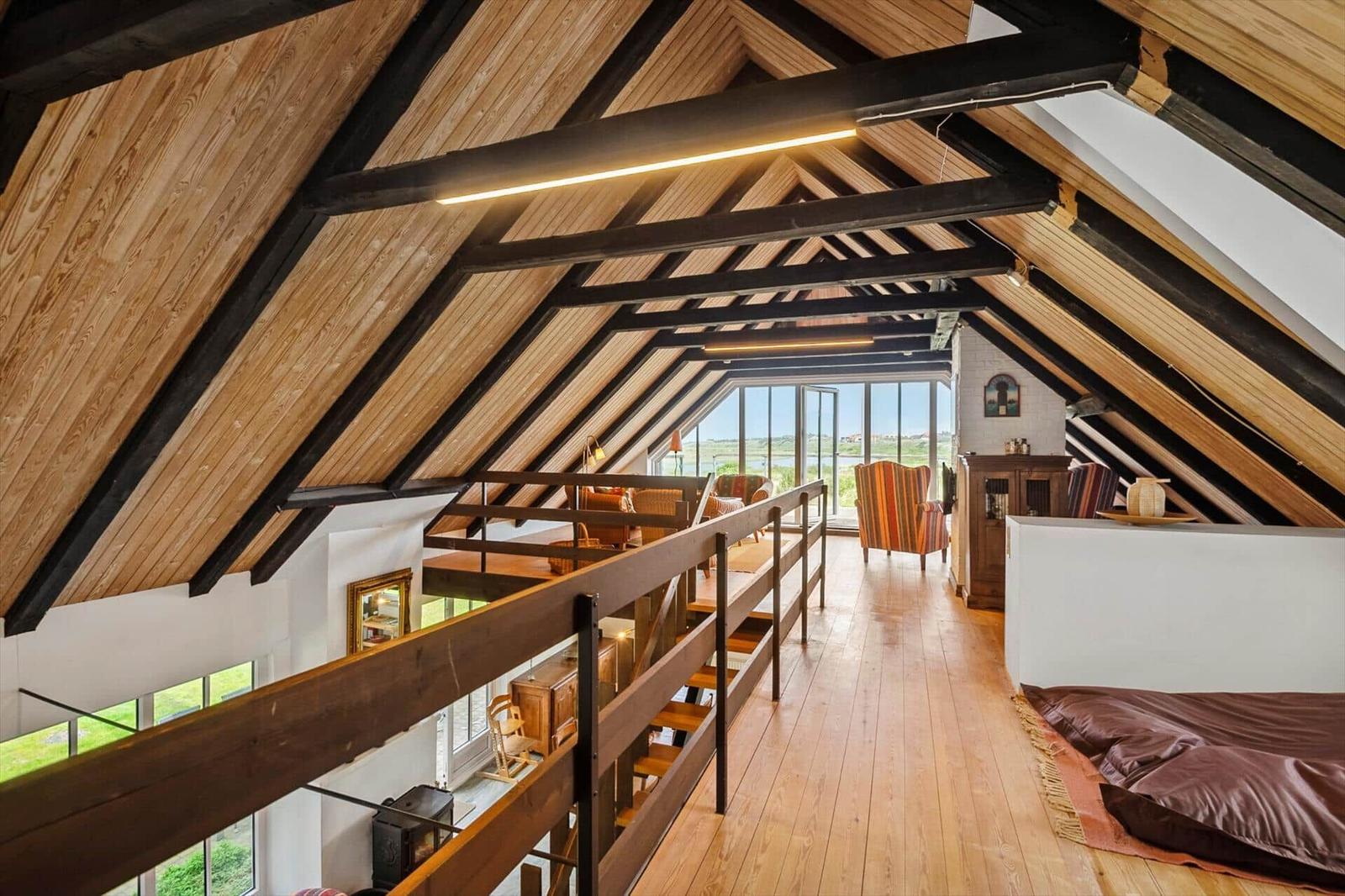Höhlenwohnung mit Holzdecke, Balkon und großem Fenster. Schlafbereich mit Bett.
