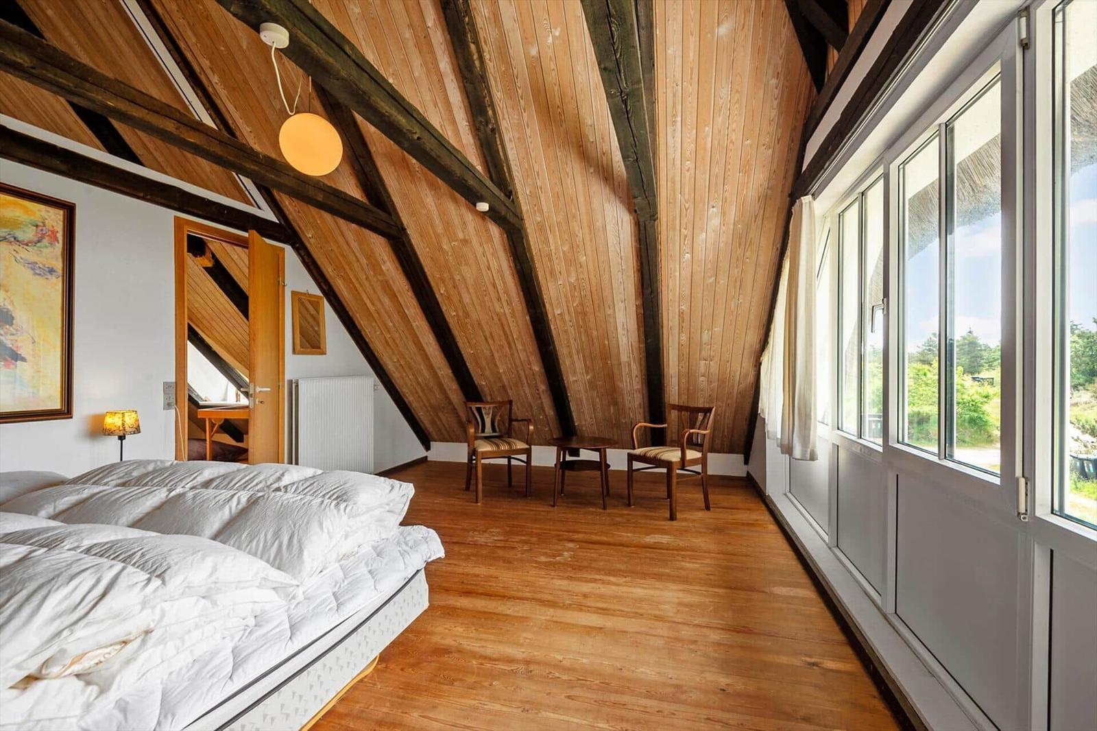 Schlafzimmer mit Holzdecke, Fenster und Bett