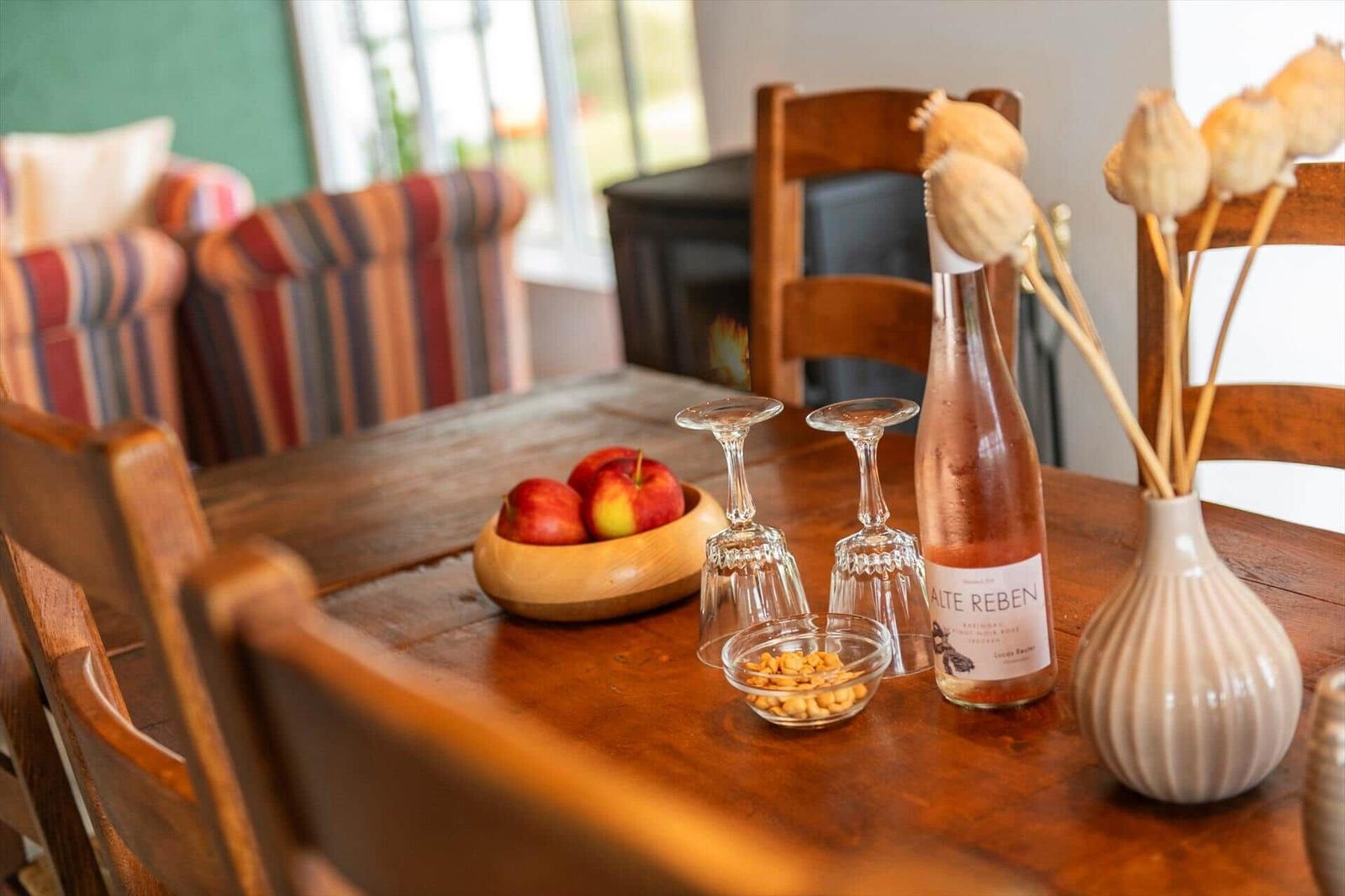 Holztisch mit Flasche, Gläsern, Apfel und Vase mit Poppys.