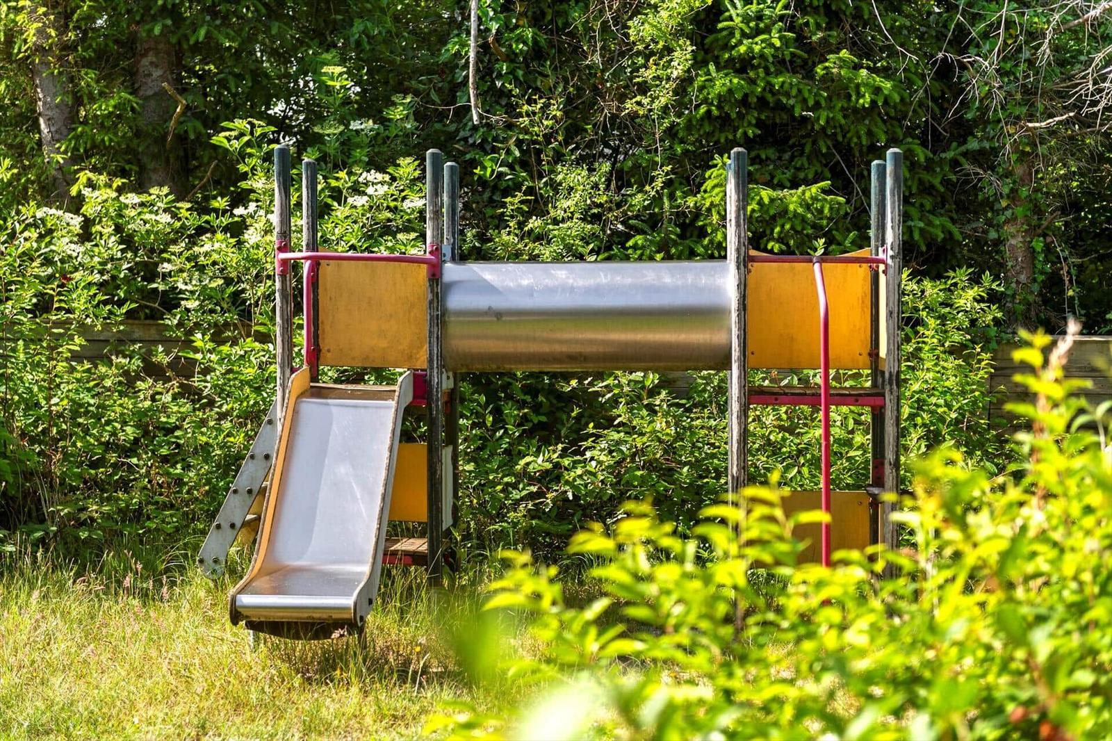 Kinder-Spielplatz mit Rutsche und Röhrenrutsche im Grün.