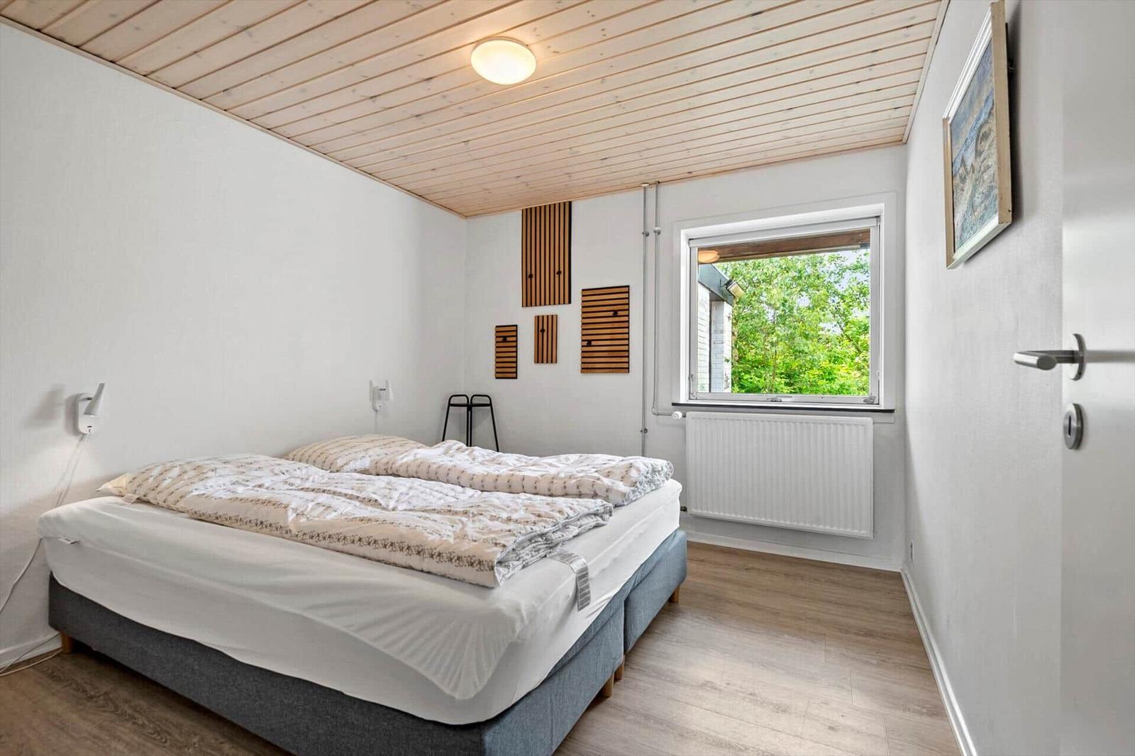 Schlafzimmer mit Bett, Fenster und Holzdecke.