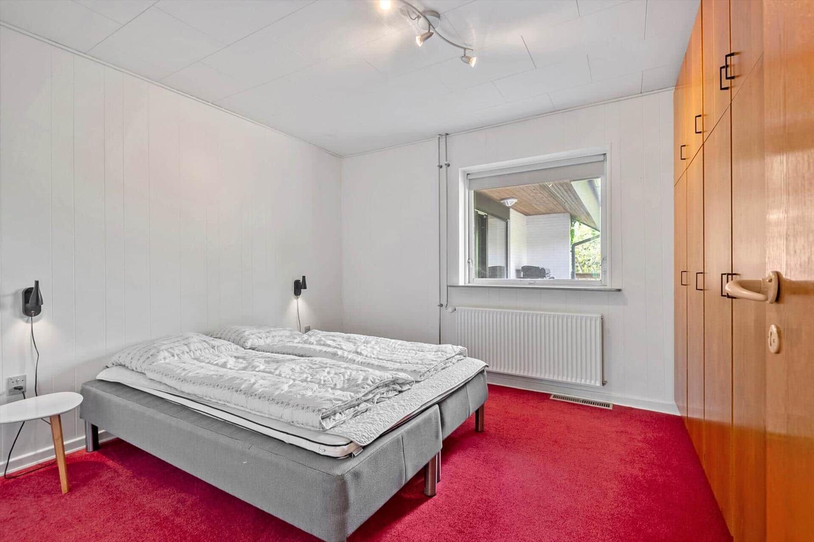 Schlafzimmer mit Bett, Kleiderschrank und Fenster.