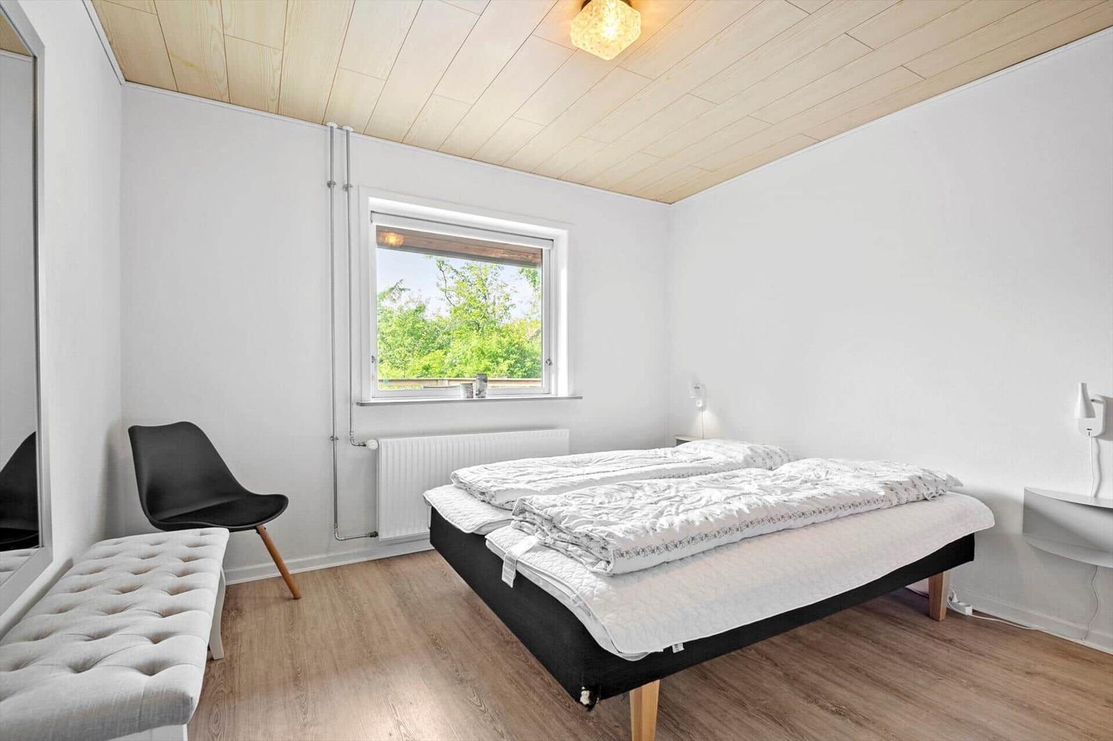 Schlafzimmer mit Bett, Fenster und Stuhl.