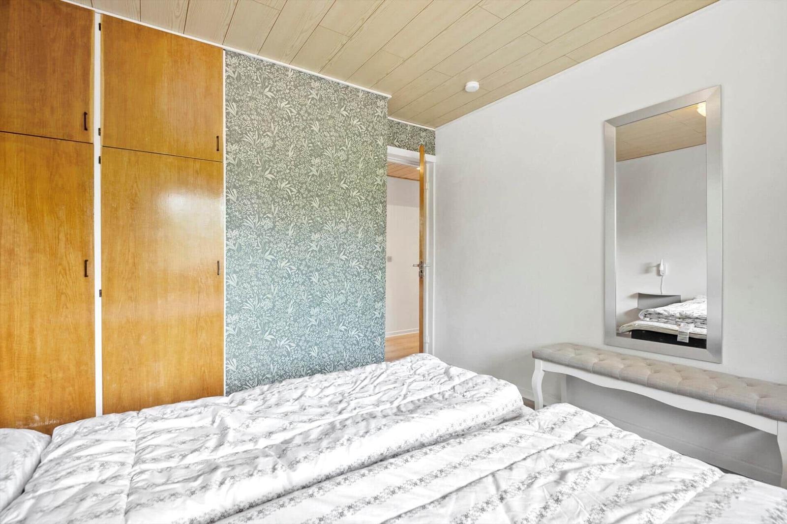 Schlafzimmer mit Bett, Kleiderschrank und Spiegel an der Wand.