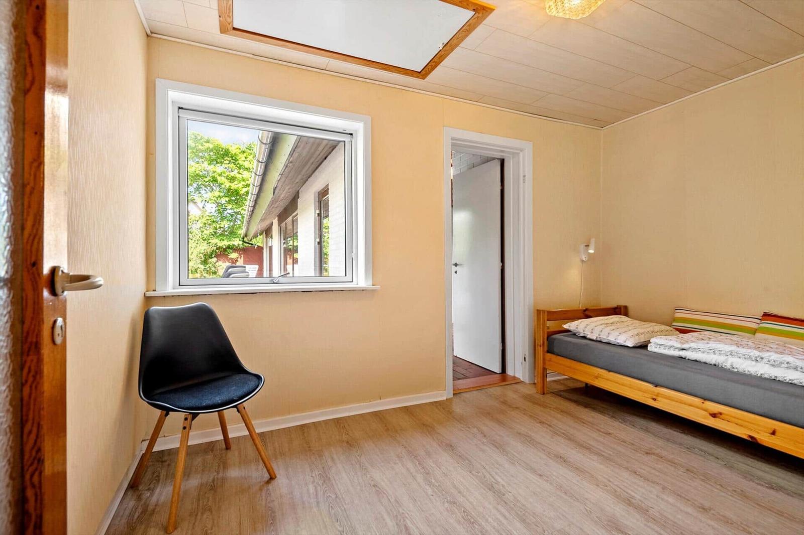 Ein Schlafzimmer mit einem Bett, einem Stuhl und einem Fenster.