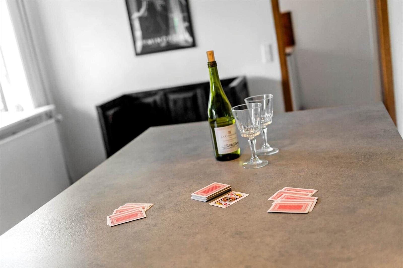 Tisch mit Weinflasche, Gläsern und Spielkarten