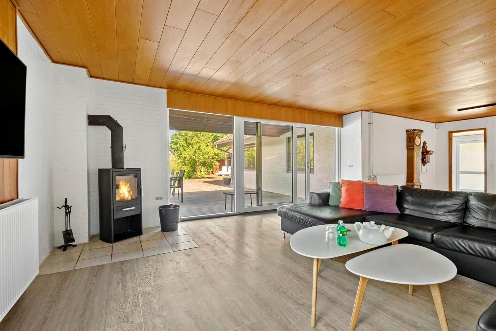 Wohnzimmer mit Kamin, Sofa und Terrassentür