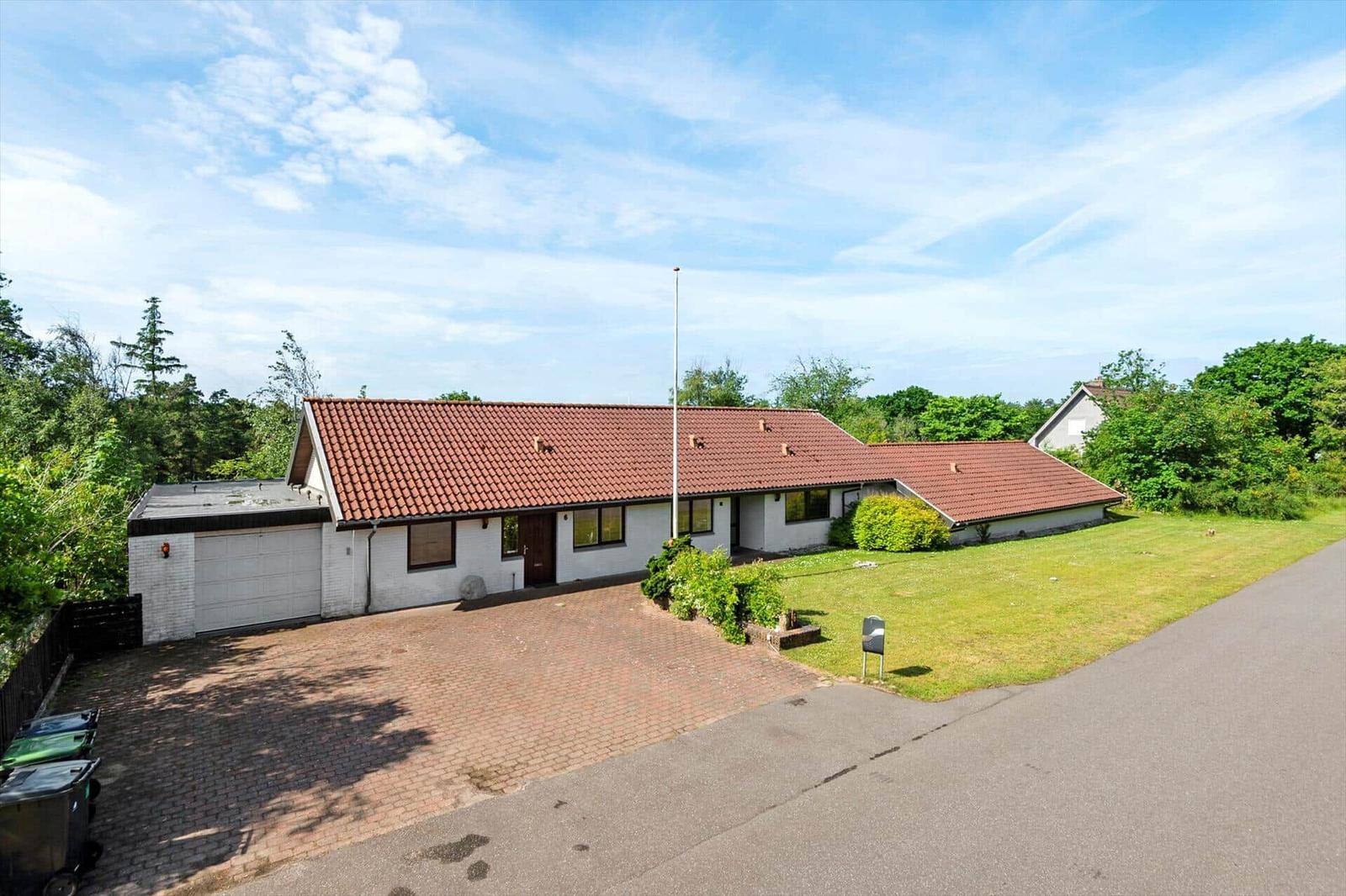 Einfamilienhaus mit rotem Dach, Garage und Rasenflächen.