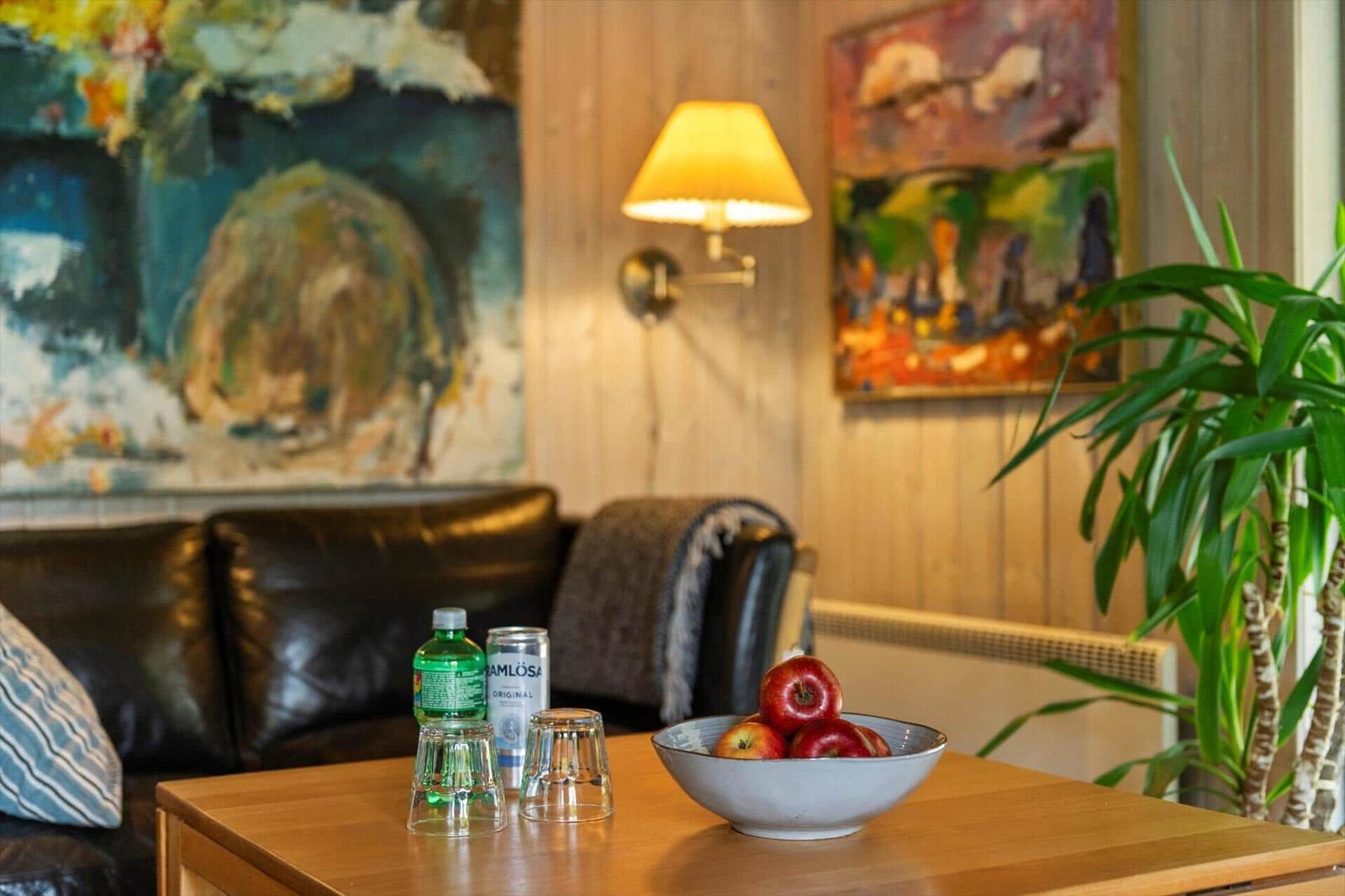 Ein Wohnzimmer mit Holzwänden, einem Sofa und einem Tisch mit Äpfeln und Getränken.