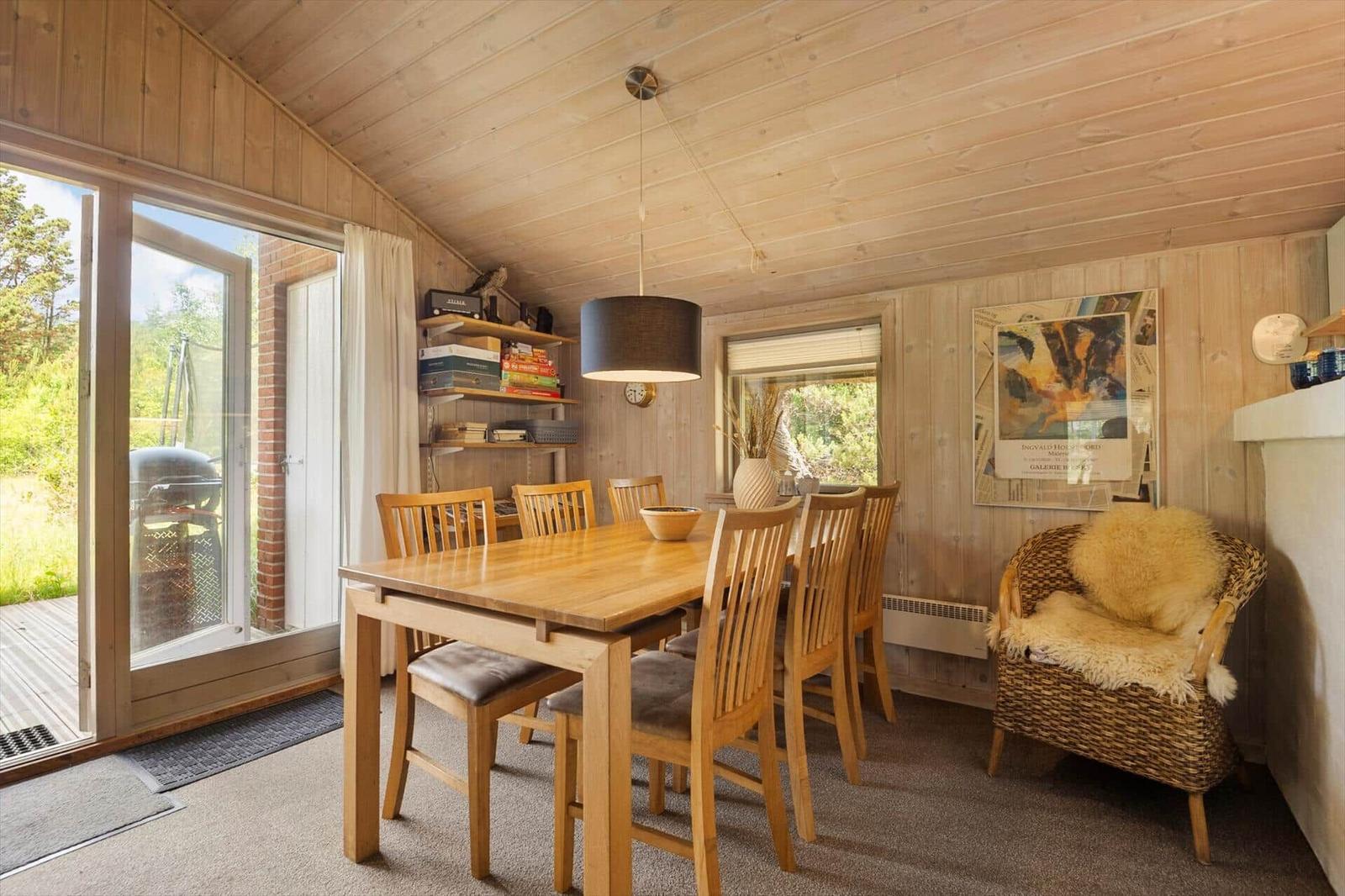 Esszimmer mit Holztisch, Stühlen und Sicht auf Balkon