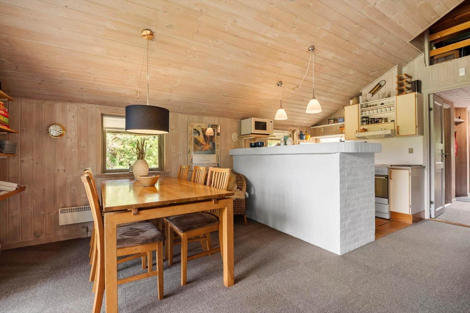 Essbereich mit Holztisch und Stühlen, Küchenbereich mit Arbeitsplatte und Geräten.