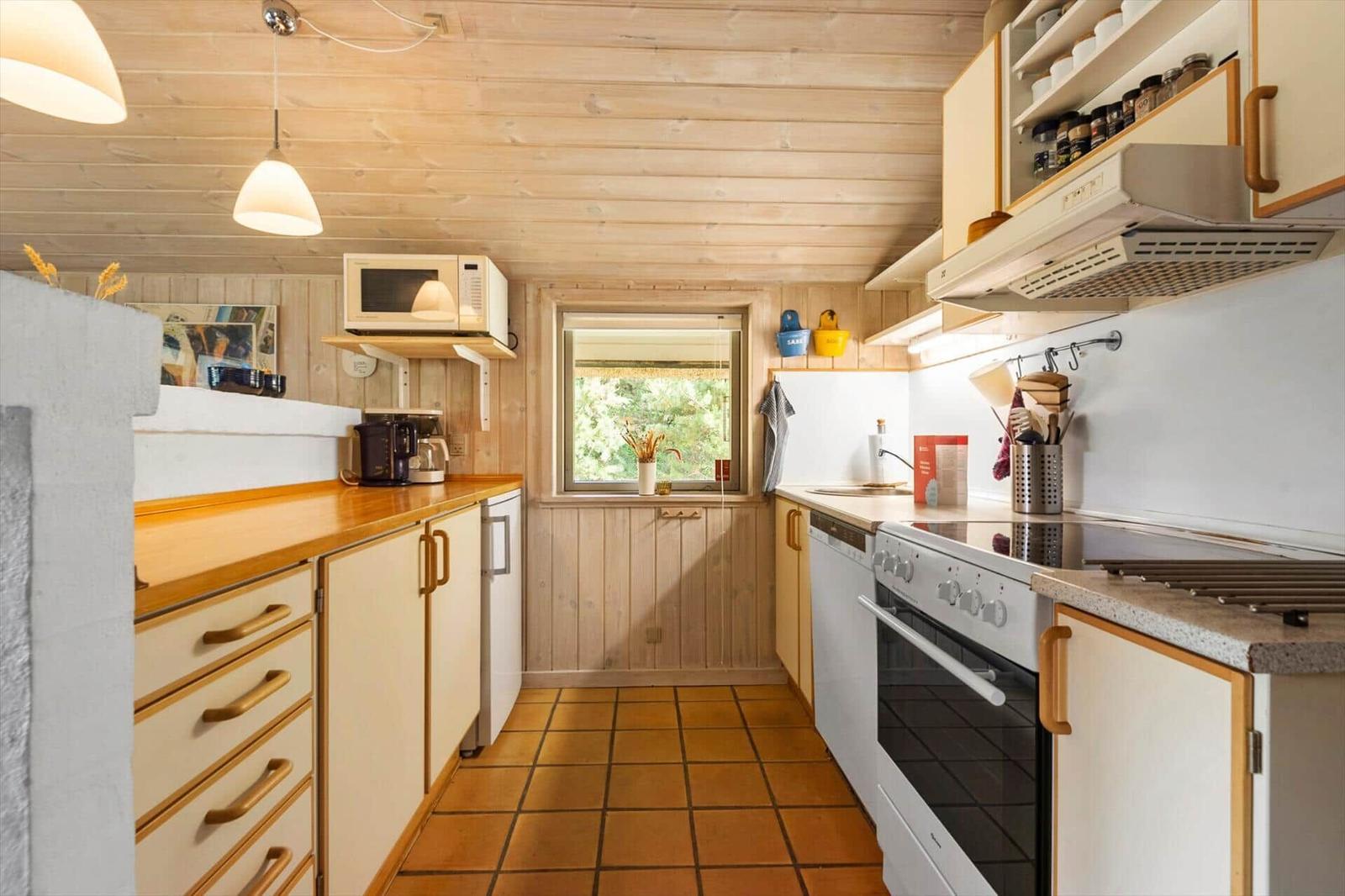 Küche mit Holzwänden, Arbeitsplatten und Küchengeräten.