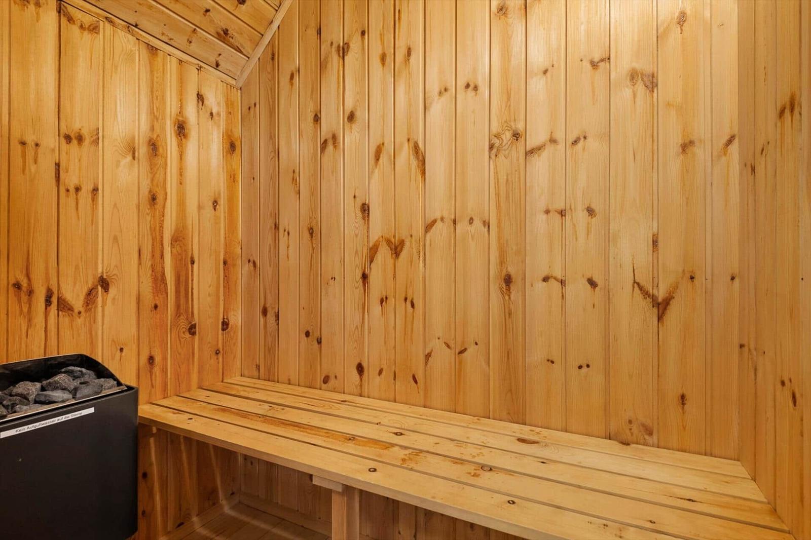 Sauna mit Holzwand und Sitzbank. Heizung mit Steinen.