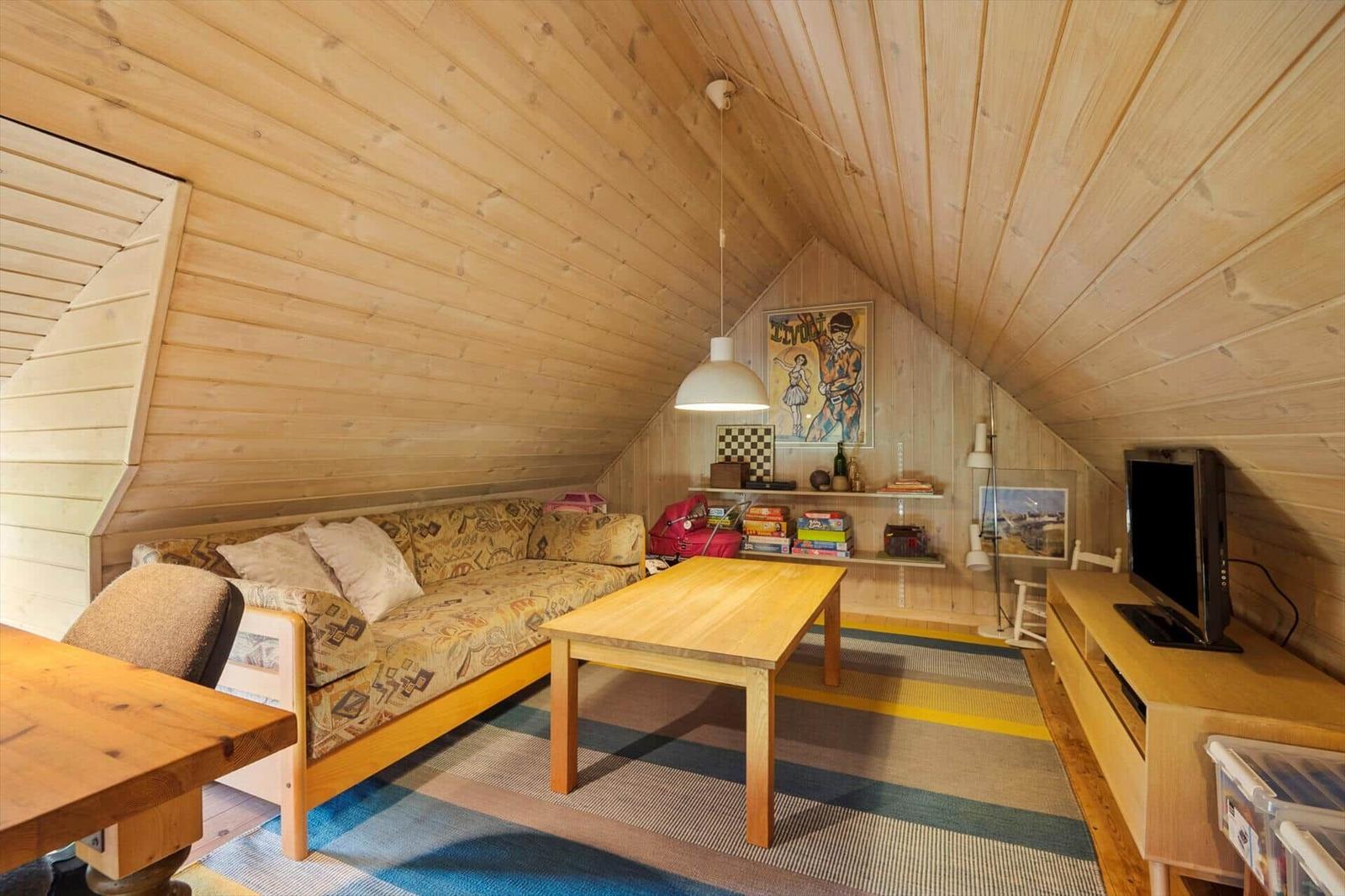 Wohnzimmer mit Holzwand, Sofa, Tisch und Fernseher