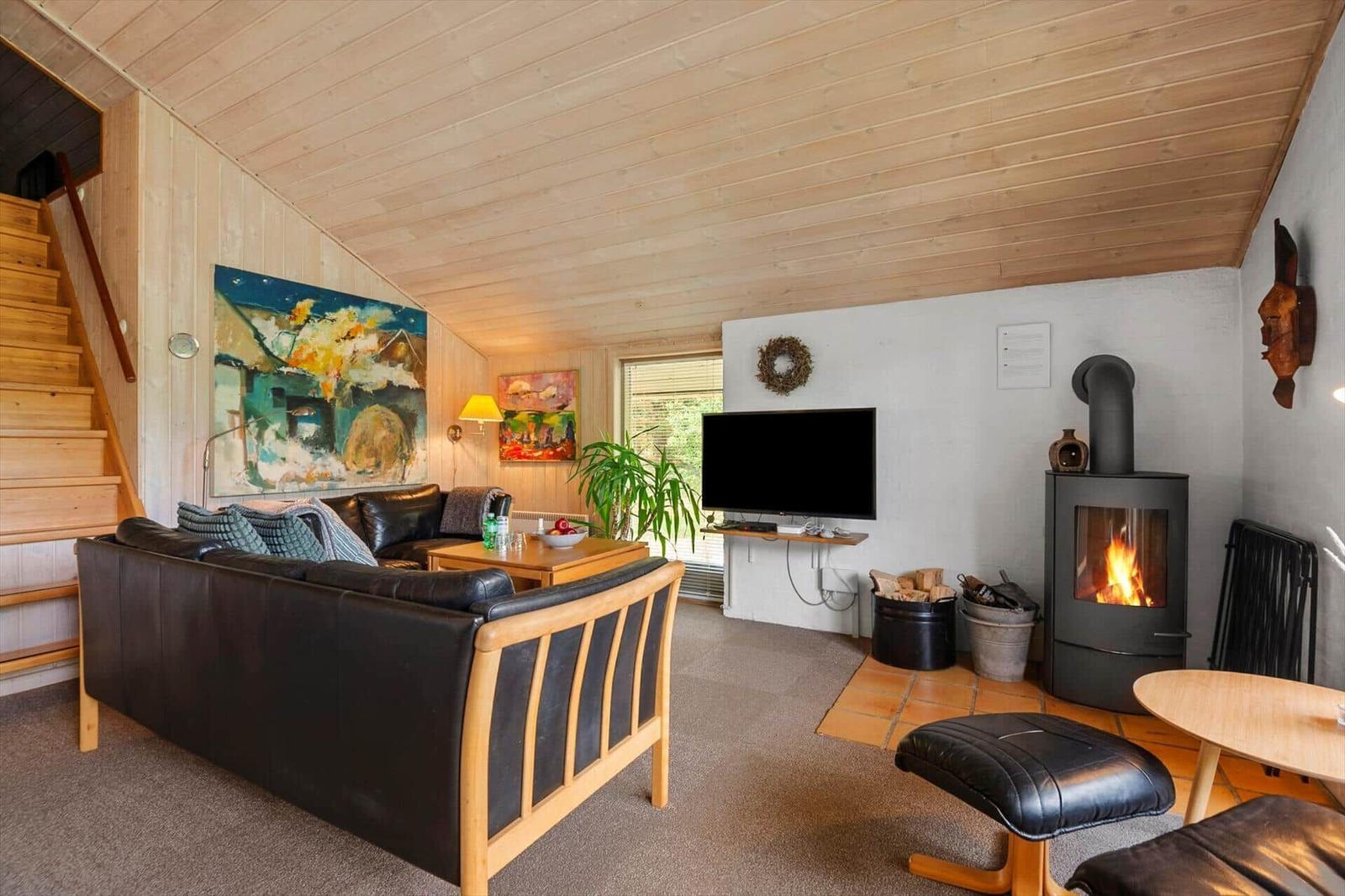 Wohnzimmer mit Sofa, Kaminofen und Fernseher an der Wand.