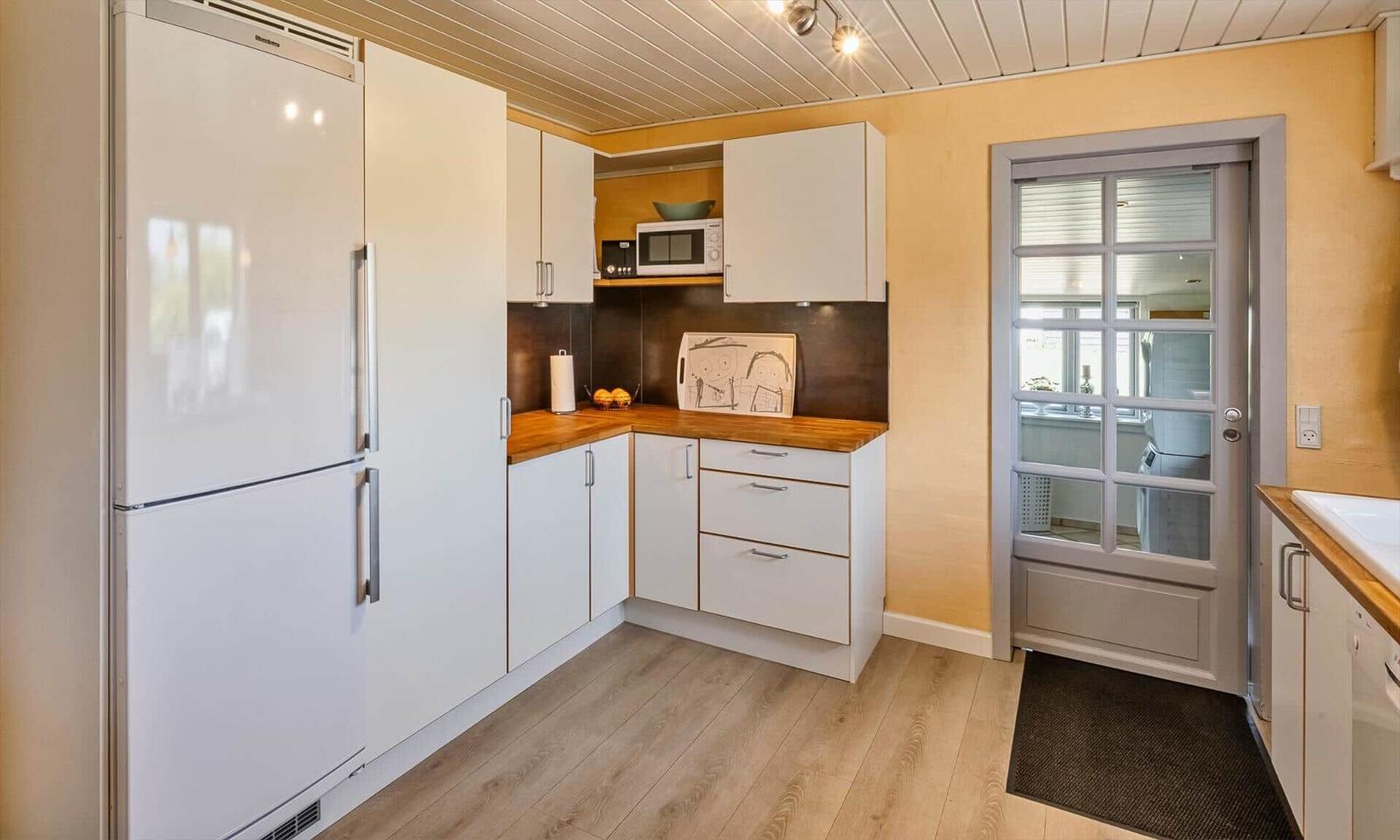 Kitchen with white built-in cabinetry, wooden countertops, and glass door to adjacent unit.