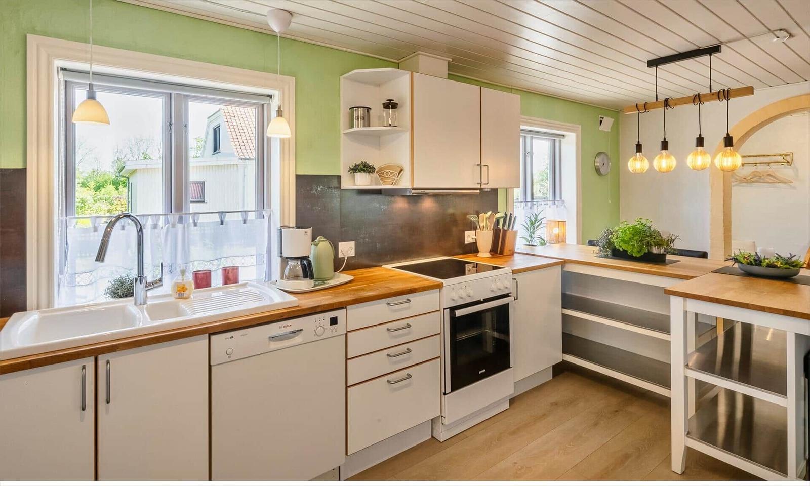 Kitchen with wooden surfaces, white cabinets, and window view.
