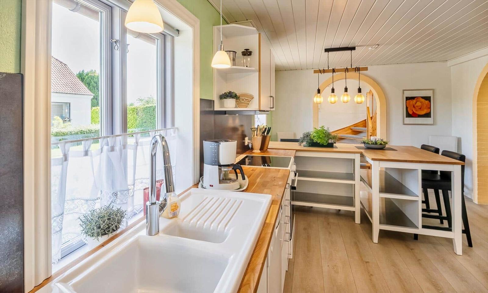 Kitchen with wooden surfaces, window, and garden view. Dining area with table and chairs.