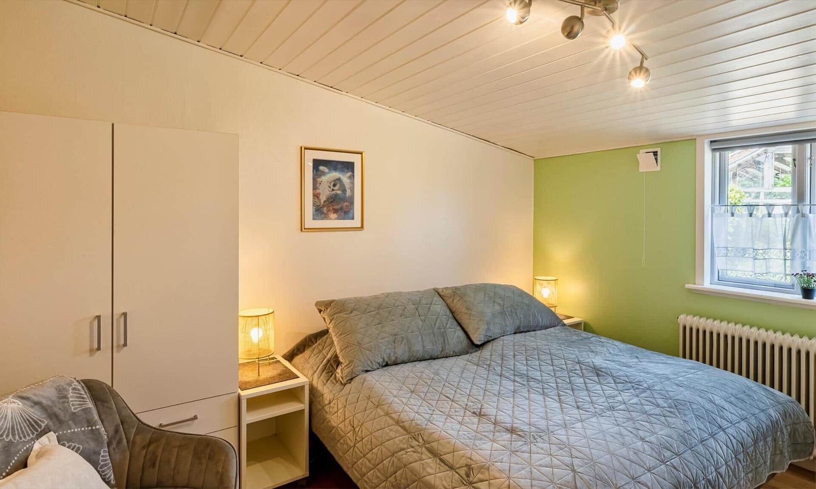 Bedroom with bed, nightstand, wardrobe, and window.