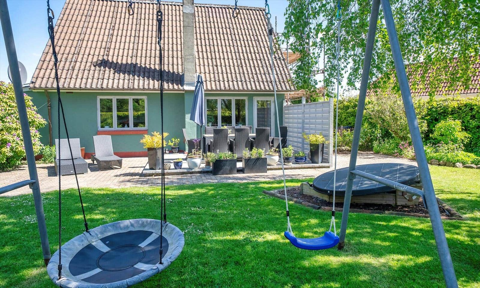 House with garden, swing, and terrace with seating.