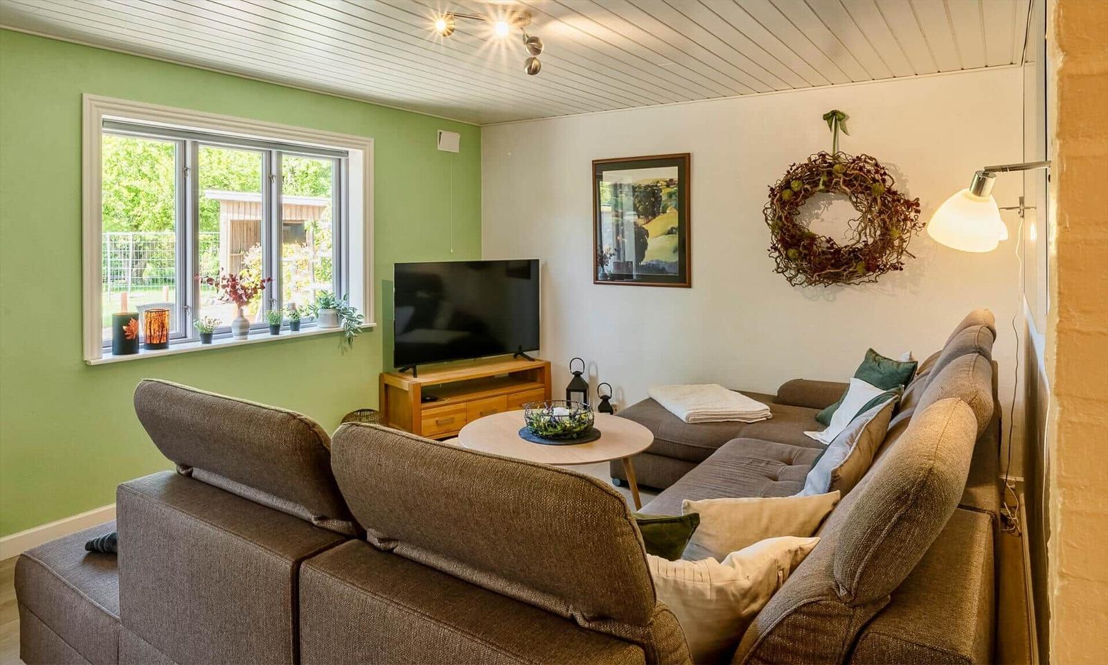 Living room with sofa, TV, and window. Wall decor and lighting.